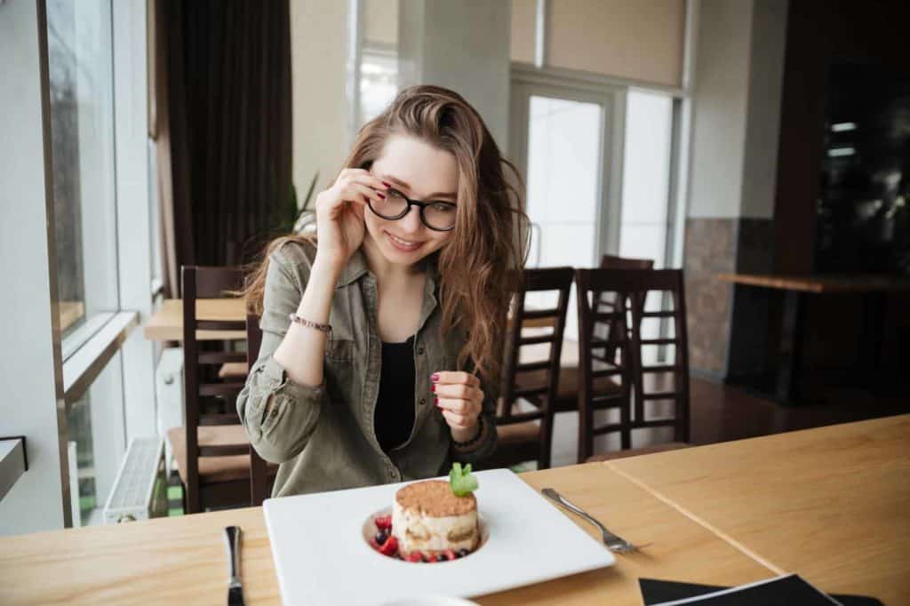 Smiling lady with long hair wearing glasses sitting in cafe