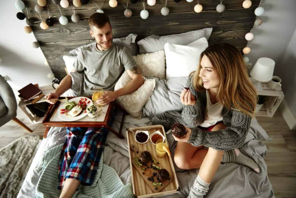 Man and woman eating breakfast on bed
